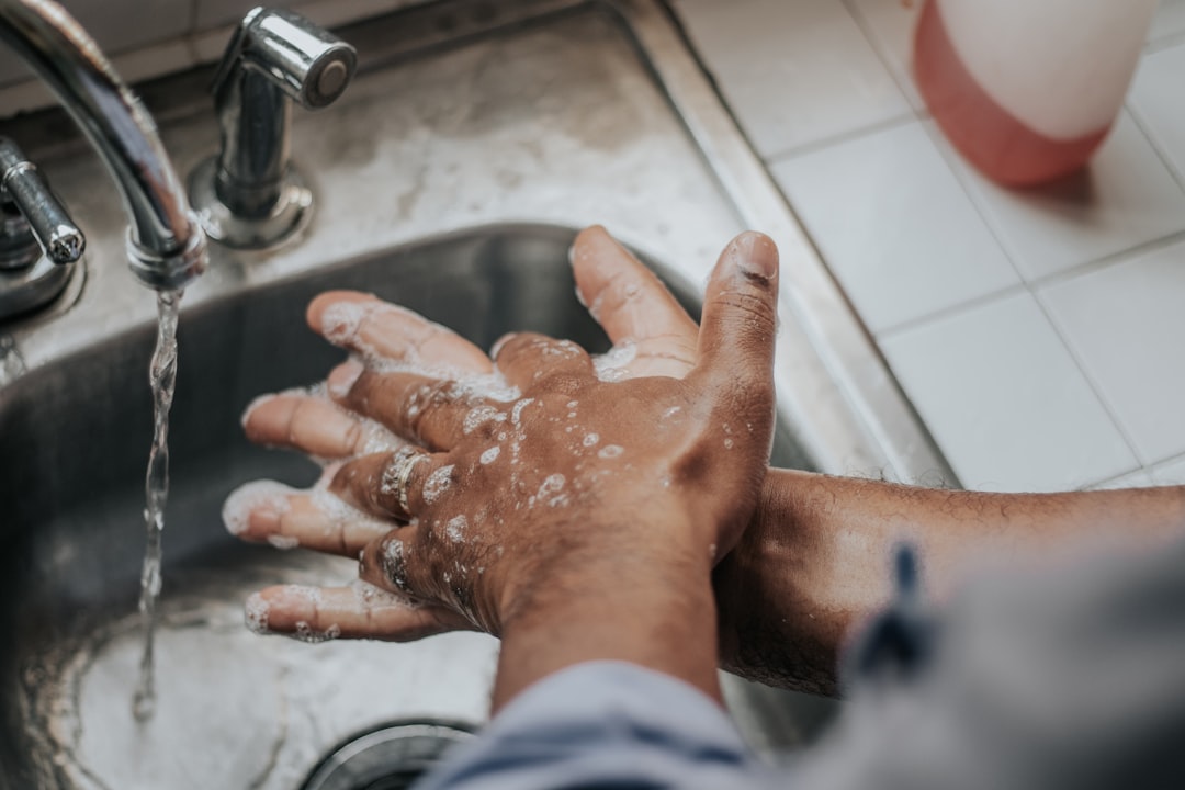 A person demonstrating proper handwashing techniques in a bright bathroom setting.